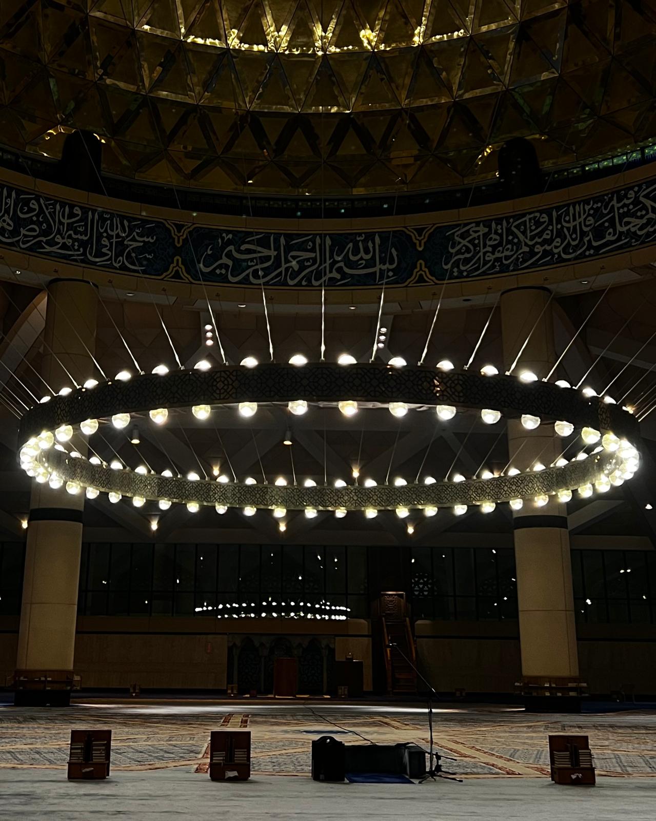Mosque interior at night, illuminated circular chandelier